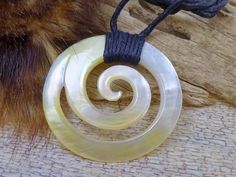 an animal's tail is shown next to a necklace with spirals on it