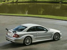 a silver sports car parked in front of a lake