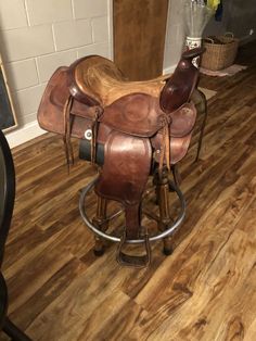 a brown horse saddle sitting on top of a wooden stool