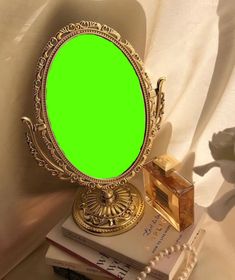 there is a green screen in the mirror on top of some books and a bead necklace