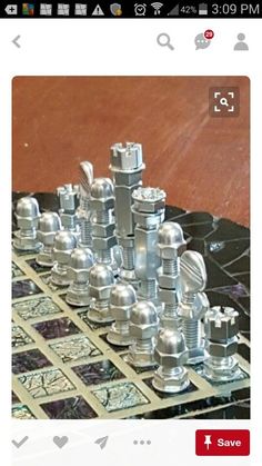 a metal chess set sitting on top of a black marble table next to a wooden floor