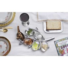 a table topped with plates and silverware next to a white cloth covered tablecloth