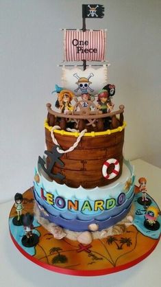 a three tiered cake decorated with cartoon characters and pirate ship on it's side