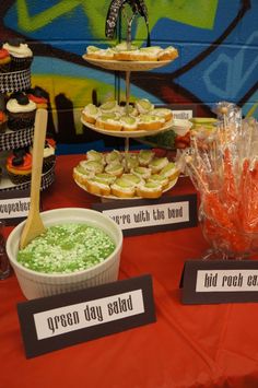 an assortment of desserts and snacks on a table in front of a graffiti wall