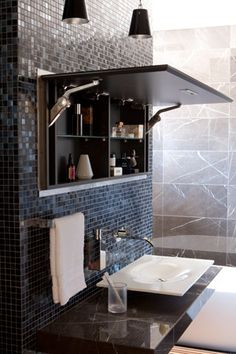 a bathroom with black and white tiles on the wall, sink and mirror in it