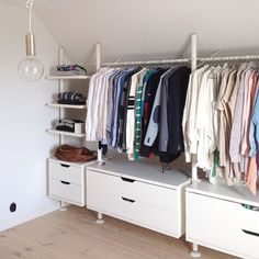 an organized closet with clothes and shoes hanging on the rack, next to a lamp