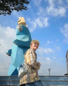 a young boy standing next to a blue bear statue