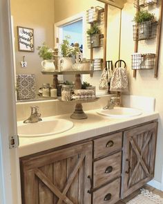 a bathroom with double sinks and wooden cabinetry in front of a mirror that has hanging planters on it