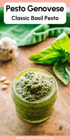 pesto genovee in a glass jar with basil leaves and garlic on the side