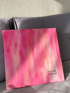 a pink painting sitting on top of a gray couch