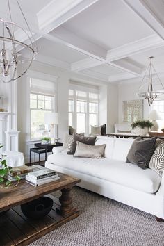 a living room filled with white furniture and lots of pillows on top of the couch