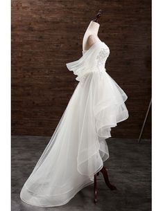 a white wedding dress on a mannequin in front of a wooden wall and floor