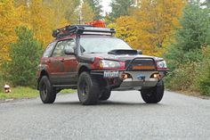 a red four - doored suv is driving down the road