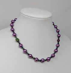 18-inch faux purple pearl necklace with iridescent accents strung on silk cording. Purple Pearl Single Strand Necklace, Adjustable Purple Beaded Pearl Necklace, Adjustable Beaded Purple Pearl Necklace, Purple Round Beads Pearl Necklace For Gift, Adjustable Purple Pearl Necklace With Round Beads, Purple Beaded Pearl Necklace, Purple Pearl Necklaces With Round Beads, Adjustable Purple Pearl Necklace, Purple Single Strand Pearl Necklace