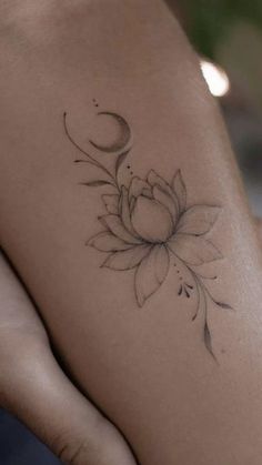 a woman's arm with a flower and crescent tattoo on the left side of her body