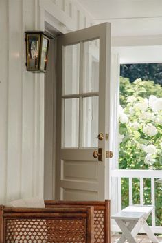 an open door to a porch next to a white chair