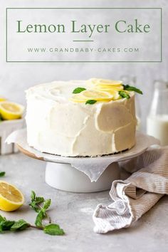 a lemon layer cake sitting on top of a white plate next to sliced lemons