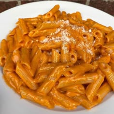 a white plate topped with macaroni and cheese covered in powdered parmesan