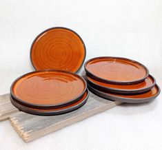 three orange plates sitting on top of a wooden board