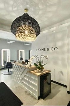 the interior of a salon with white walls and black accents on the ceiling, chandelier hanging from the ceiling