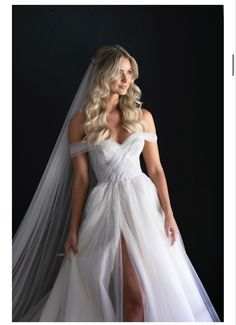 a woman in a white wedding dress posing for the camera with her veil over her head