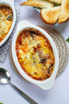 two bowls of food with bread on the side