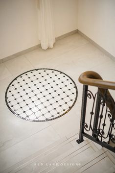 a white tiled floor with black and white designs in the center, next to a metal hand rail