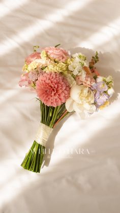 a bouquet of flowers sitting on top of a white bed sheet with the sun shining through it