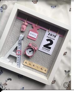 a white frame with pink items in it and a ruler on the wall next to it