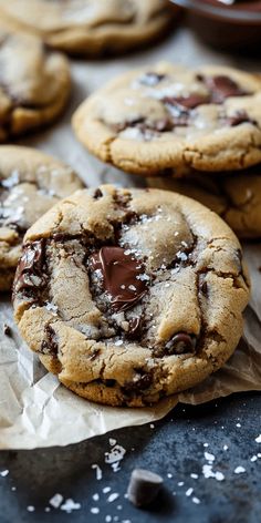 chocolate chip cookies with sea salt on top and one broken in half, sitting on wax paper