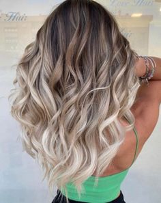 the back of a woman's head with long, wavy hair in front of a store window