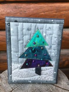 a small patchwork christmas tree on top of a log