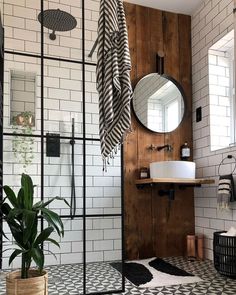 a bathroom with black and white tile, wood paneling and a round mirror on the wall