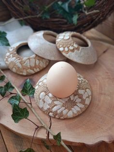 an egg sitting on top of a piece of wood next to some leaves and ivy