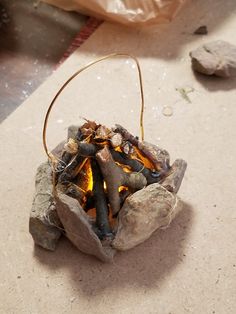 an open fire pit sitting on top of a table next to rocks and a bag