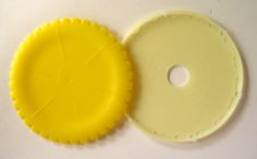 two pieces of yellow plastic sitting next to each other on a white surface with holes in the middle