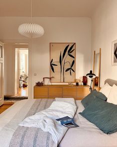 a bedroom with a bed, dresser and artwork on the wall