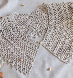 two crocheted shawls sitting on top of a white cloth covered in beads