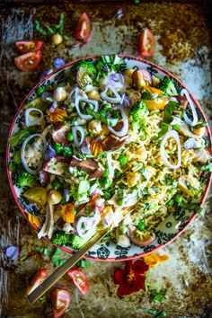 a salad with onions, broccoli and other vegetables in a bowl on a table