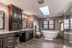 a large bathroom with wooden floors and dark wood cabinetry, along with a claw foot tub