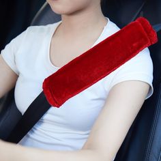 a woman sitting in the back seat of a car with a red pillow on her arm