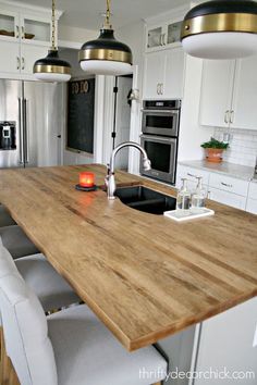 a kitchen island with chairs and lights hanging from it's ceiling in front of an oven