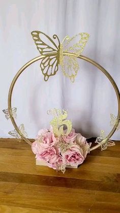 a gold butterfly headband with pink flowers on a wooden table next to a white wall