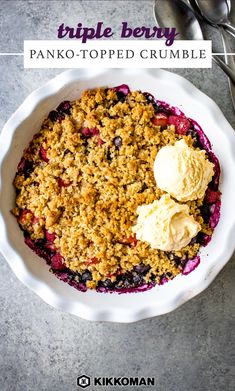 a white bowl filled with blueberry crumble and ice cream next to spoons