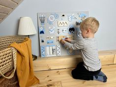 a young boy sitting on the floor playing with magnets and paper decorations in front of him