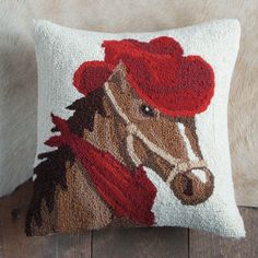 a decorative pillow with a horse wearing a red hat on it's head, sitting on a wooden floor