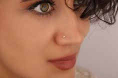 a close up of a woman's face with an ear piercing on her nose