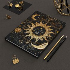 a black and gold notebook with the sun and moon on it, surrounded by other items