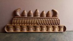 a wooden carving of a row of toothbrushes on top of a table next to a wall