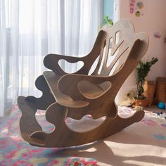 a wooden rocking chair sitting on top of a carpeted floor next to a window